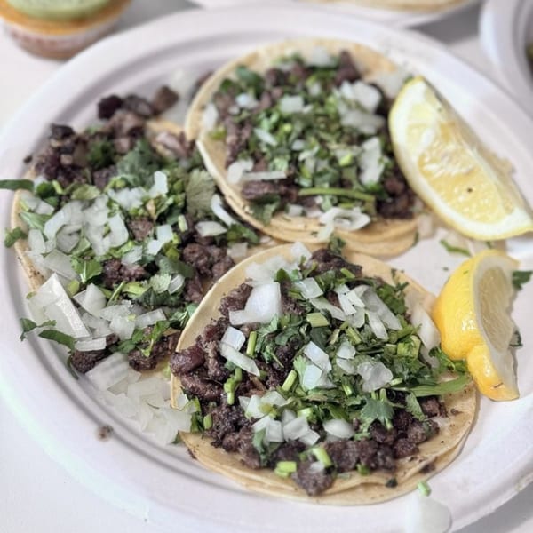 Three Cheztakos!!! tacos with meat, cilantro, onions, and lemon wedges on a white plate.